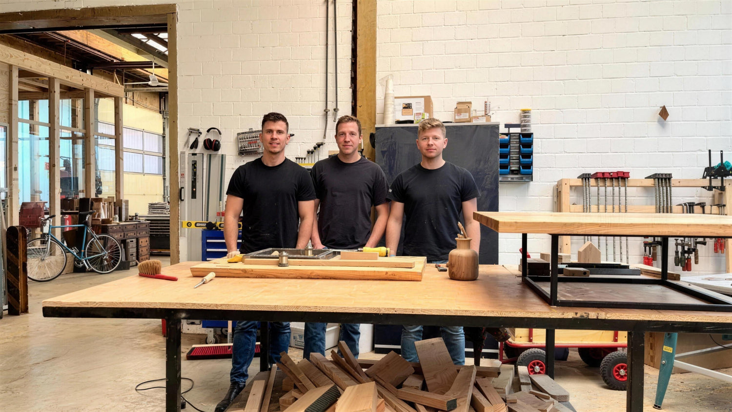 Das Holzpause-Team in der Werkstatt in Damme: drei Gründer hinter der Werkbank mit Eichenholz
