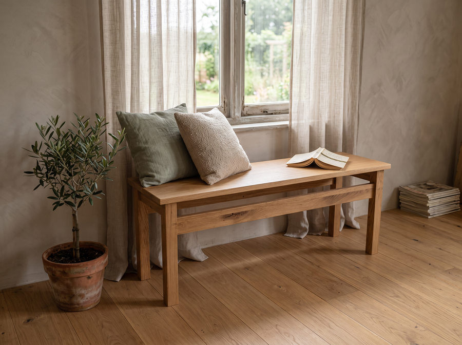 Sitzbank mit Querstrebe unter dem Fenster mit Kissen und Buch